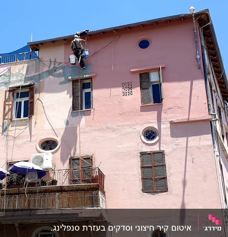 אדם על חבל אוטם קיר חיצוני של בניין